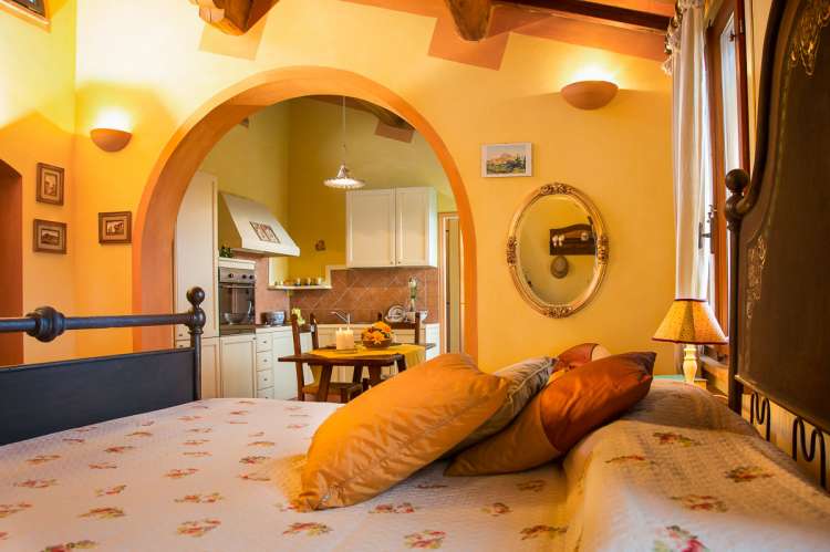 Bildet viser oppholdsrommet i ferieleiligheten Melograno på La Pergola med dobbeltseng og åpning mot kjøkkenet.  Ved Pisa i Toscana.
