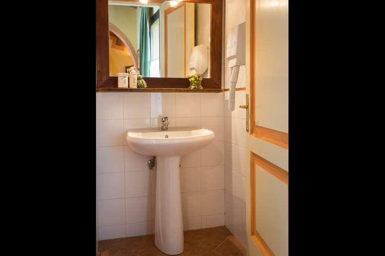 Bildet viser badet med servant og speil i ferieleiligheten Melograno.  På feriebostedet La Pergola ved Pisa i Toscana.