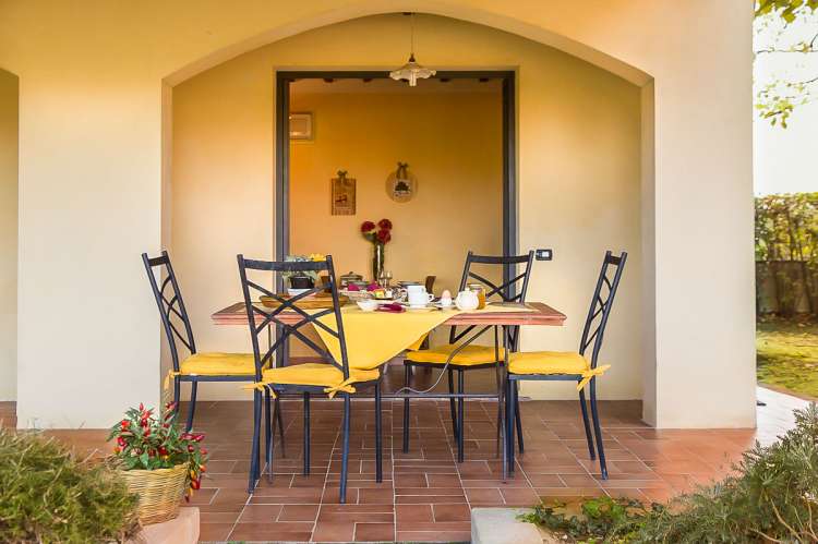 Bildet viser terrassen med oppdekket spisebord utenfor ferieleiligheten Uva. På feriebostedet La Pergola ved landsby i Toscana.
