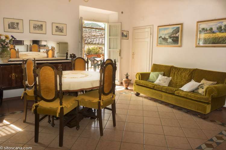 Foto fra stua i ferieboligen med spisebord, sofa og dør ut til terrassen. 