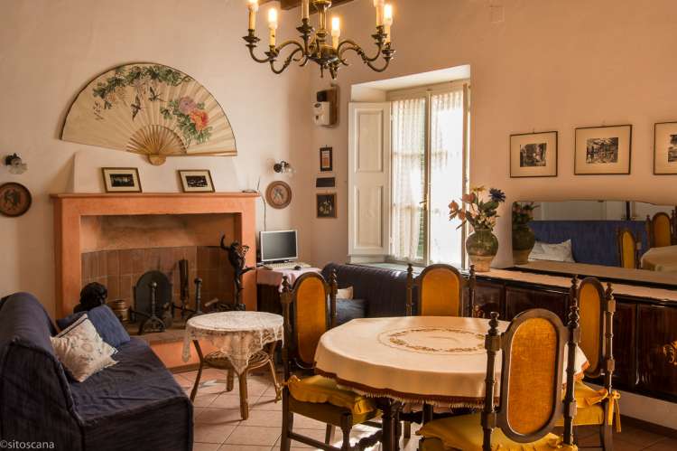 Foto fra stua i ferieboligen med spisebord, to sofaer og peis. Vindu ut mot terrassen.