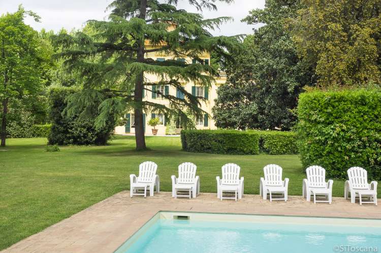 Bildet viser basseng og solstoler utenfor villa til utleie ved Pisa i Italia.