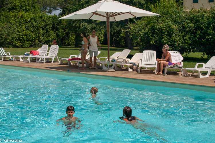 Bildet viser barnefamilie på ferie i Toscana som koser seg rundt bassenget ved feriehuset. 