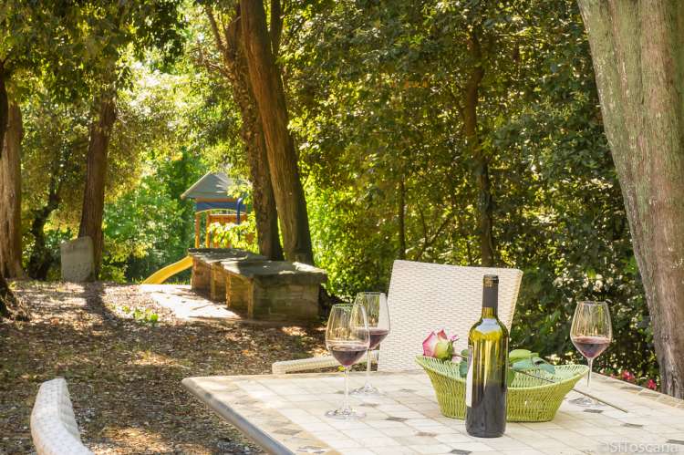 Bildet viser italiensk vin på terrasse med lekeplass i bakgrunnen. Feriehus i Toscana.