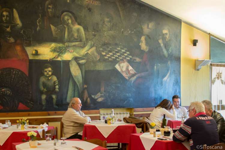Bildet viser restaurant Genovini innendørs. Stort veggmaleri og mann som spiser. Nært ferieboligen Castrum Moriori, villa med ferieleiligheter midt mellom Pisa og Firenze.