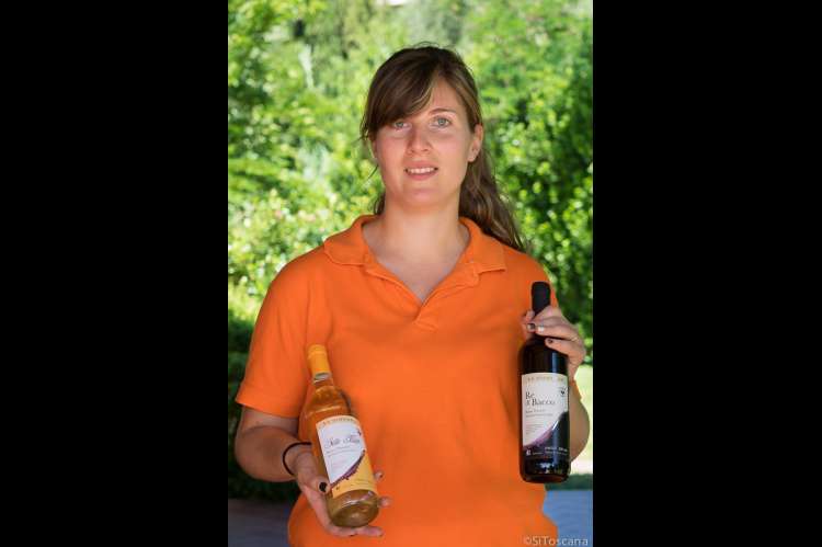 Foto av vertinnen på vingården der du kan leie ferieleilighet. Hun viser to av gårdens viner.