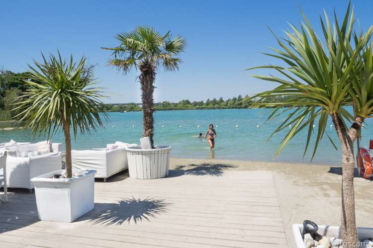 Amalia Laghi (21 km) med sandstrand, restaurant og kafè samt mulighet for å leie solseng og parasoll. Bildet viser sandstrand ved innsjø, badeliv nært olivengården Vivaio med ferieleiligheter.