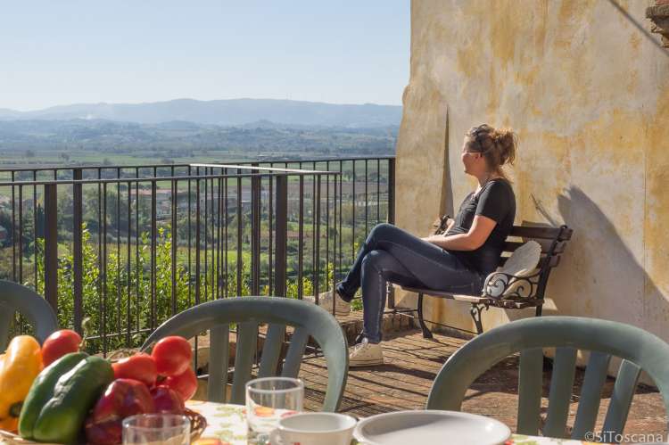 Rolig stund med flott utsikt fra terrassen i Canonica. Bildet viser terrasse med utsikt i ferieleiligheten Canonica på vingården Borgo Etruschi sentralt i Toscana.