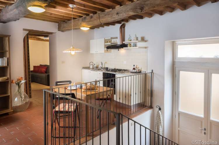 Bildet viser kjøkken og del av stua i ferieleilighet i middelalderlandsby utenfor Pisa.