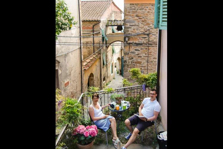 Uteplass med utsikt til vakre steinhus, typisk landsbybebyggelse i Toscana. Hortensia i terracottakrukke. Foto.