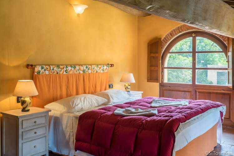 Bildet viser soverom med dobbeltseng i feriehuset Casa Diana med privat basseng og hage ved Pisa.