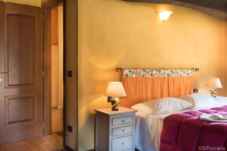 Bildet viser soverom med dobbeltseng og inngang til bad i feriehuset Casa Diana med privat basseng og hage ved Pisa.
