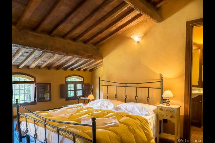 Bildet viser soverom med dobbeltseng og eget bad i det toskanske feriehuset Casa Diana i landsby med privat hage og basseng.