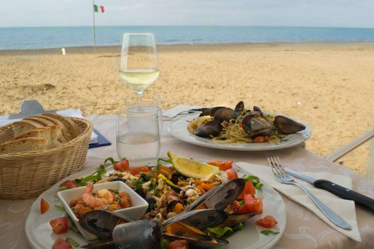 Bildet viser oppdekket bord på strand ved sjøen i Toscana.