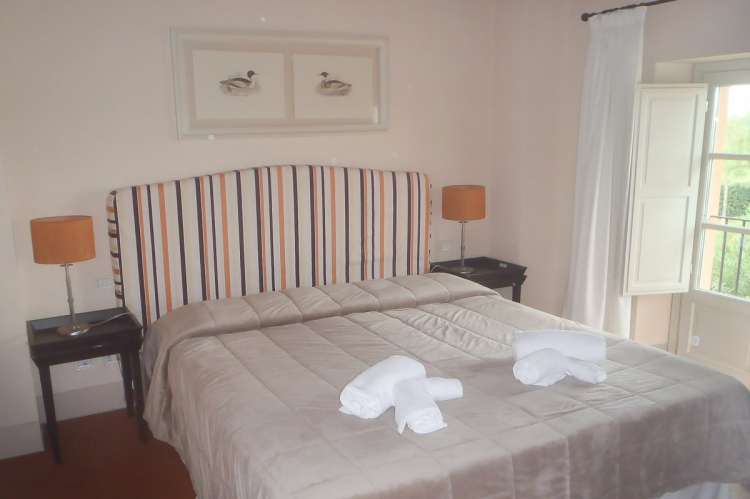 Bildet viser soverom med dobbeltseng i feriebolig nært kysten i Toscana.