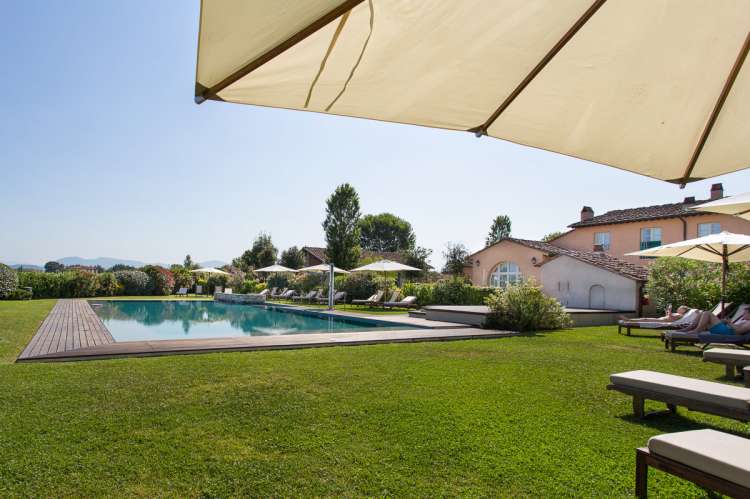 Bildet viser basseng og gressplen på feriebosted ved kysten i Toscana.