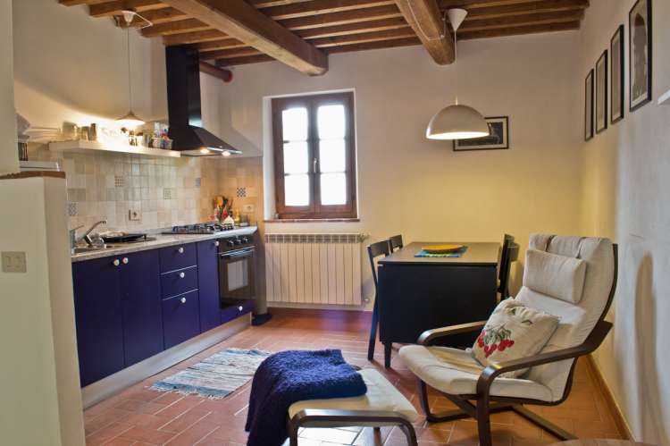 Oppholdsrom med kjøkken. Kjøkken med god standard i ferieleiligheten Casetta Livia. Spisebord og 2 lenestoler. Bilde.