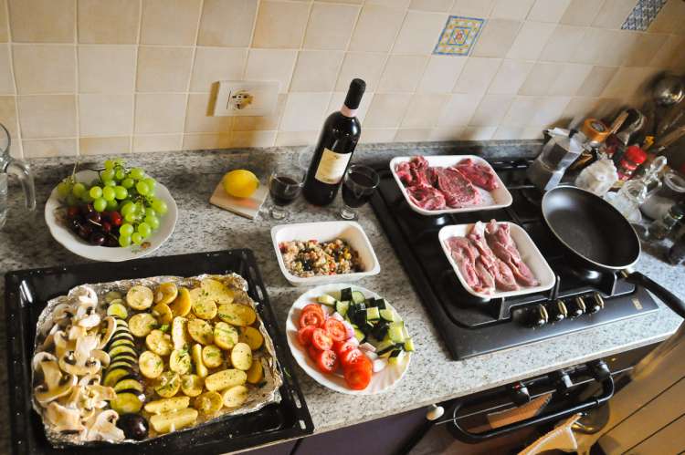 Festforberedelser på kjøkkenet. Feiring av årsdag med mat til et stort italiensk måltid på kjøkkenbenken. MFoto av mat og vin i Toscana.