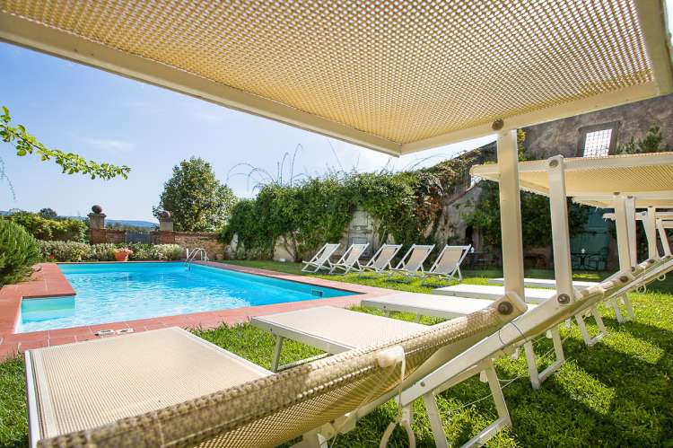 Bildet viser basseng med solstoler i hagen ved feriehuset Palazzo Pietro. Huset ligger i Toscana mellom Pisa og Firenze.