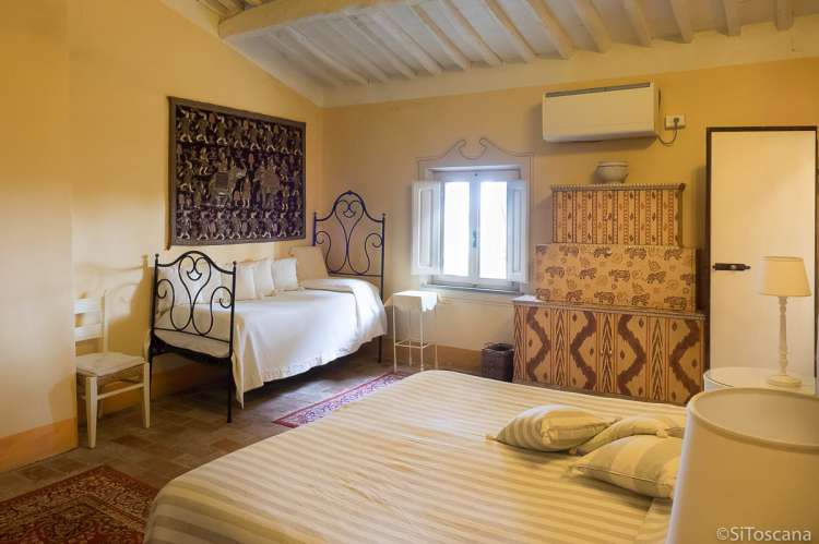 Bildet viser soverom med dobbeltseng og enkeltseng i stor villa med utsikt i Toscana.