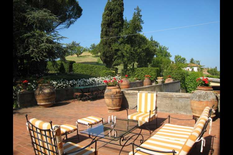 Bildet viser terrasse med utsikt til sypresser i feriehus i Toscana.