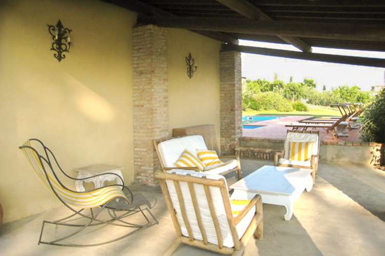 Bildet viser terrasse med sofa ved bassenget i feriehuset Villa Sole ved Pisa i Italia.