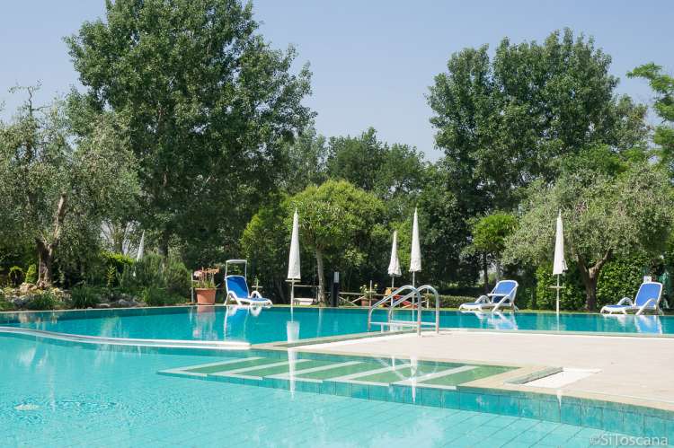 Bildet viser stort basseng i hagen til feriehus i landsby i Toscana.