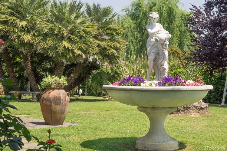 Bildet viser blomster og fontene i hagen til familievennlig feriehus i landsby ved Pisa.