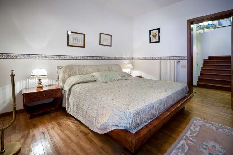 Bildet viser soverom med dobbeltseng i feriehus med stort basseng nært Pisa.