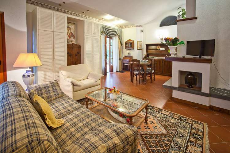 Bildet viser stue med peis i feriehus med basseng i landsby i Toscana.