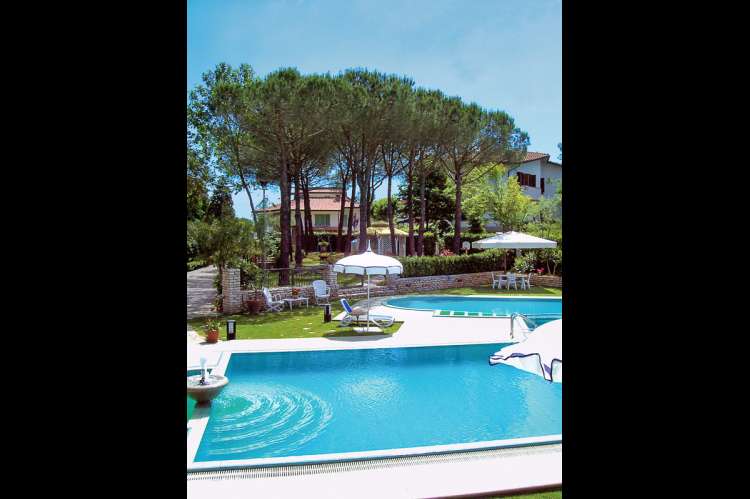 Bildet viser basseng, parasoller og sypresse i barnevennlig feriehus i Toscana.