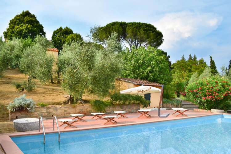 Bildet viser bassenget i hagen på Villa Alba. Ved bassengkanten er det en parasoll og bassengmøbler.