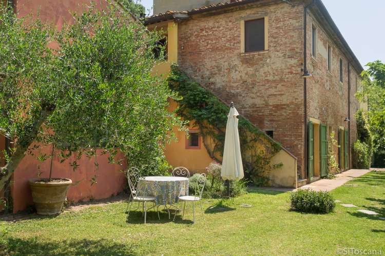 Bildet viser feriehus og hage på feriebosted med utsikt i Toscana.