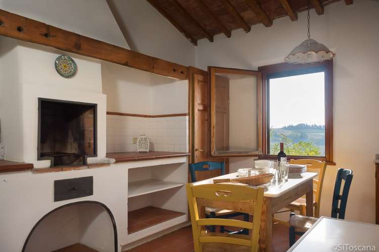 Bildet viser kjøkken med spisebord og utsikt i feriehus på gård nært Pisa.
