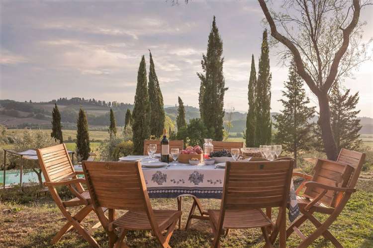 Bildet viser utsikt og spisebord ved basseng utenfor feriehus i Toscana.