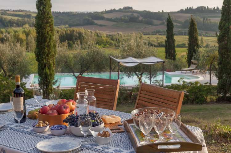 Bildet viser langbord ved basseng på olivengård med ferieboliger nært Pisa og Firenze.