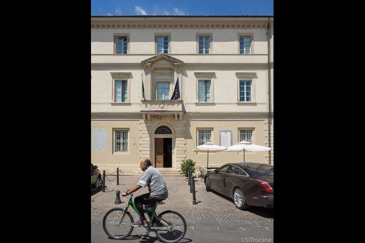 Bildet viser mann på sykkel i gate i landsby ved Pisa.