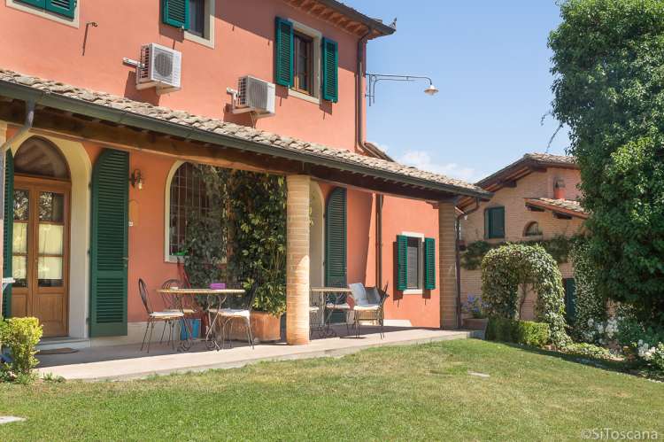 Bildet viser hus med terrasse og gressplen på olivengård ved Pisa.