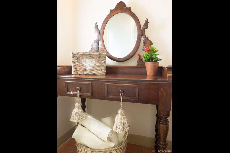 Bildet viser kommode med speil i ferieleilighet på olivengård i Toscana.