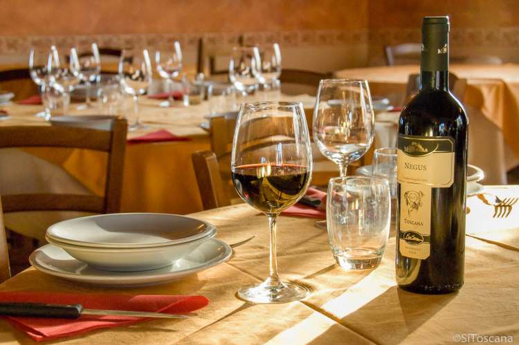 Bildet viser et oppdekt bord på en restaurant ved San Miniato. Det er rødvin på bordet.