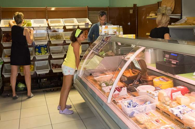 Bildet viser barn på matbutikk med ferske grønnsaker i landsby i Toscana.
