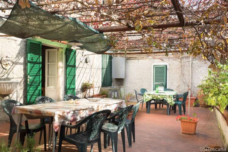 Terrassen på 60 kvm har blomstrende pergola i sommermånedene. Bildet viser stor terrasse under pergola i feriehuset Terrazza i landsby i Toscana.