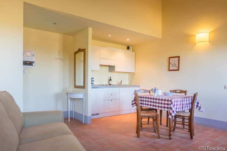 Bildet viser sofa, kjøkken og spisebord i ferieleilighet på vingård i Toscana.