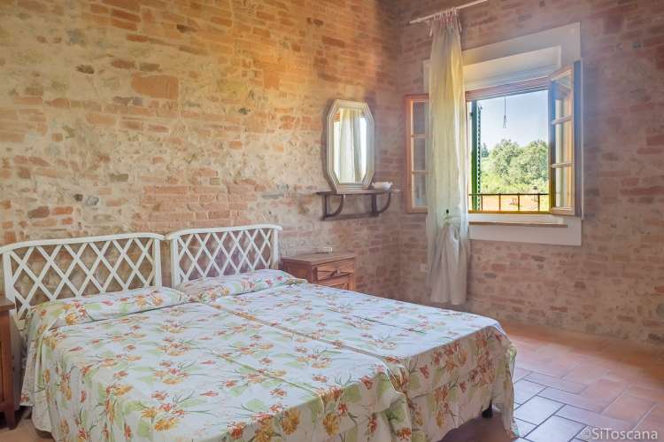 Bildet viser soverom med murvegg i feriehus på vingård i Toscana.