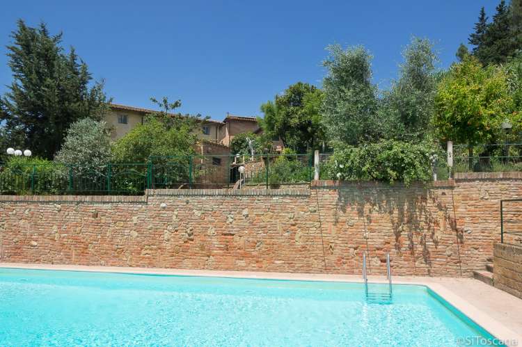 Hovedbygningen i bakgrunnen. Bildet viser basseng på vingård i Toscana.