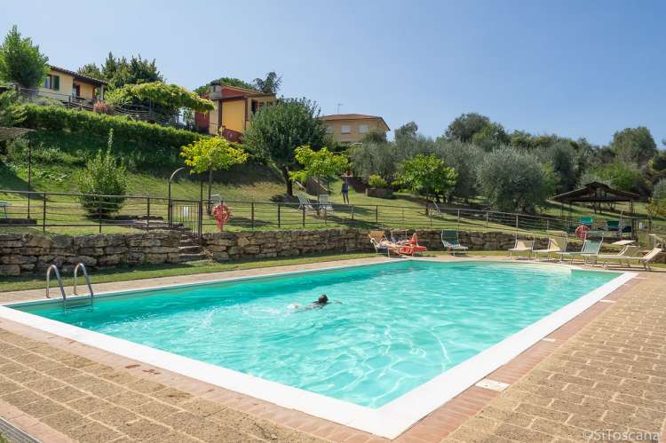 Rundt bassenget er det frukttrær og oliventrær. Bildet viser basseng med ferieleiligheter i Toscana.