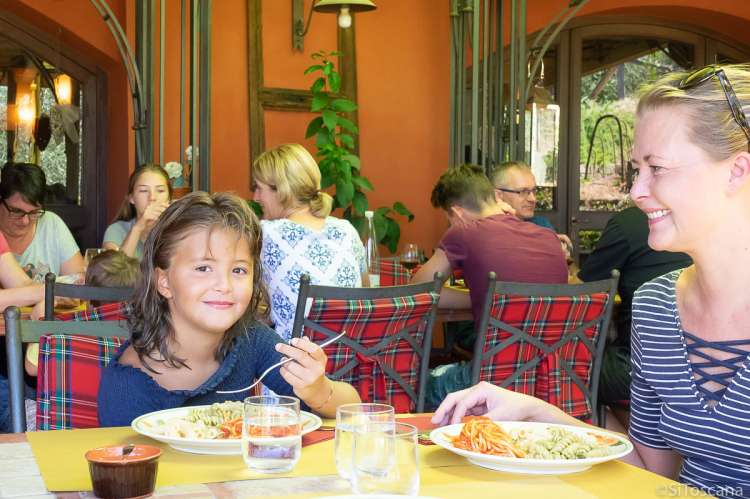 Bildet viser mor og barn som spiser pasta på restaurant i Toscana.