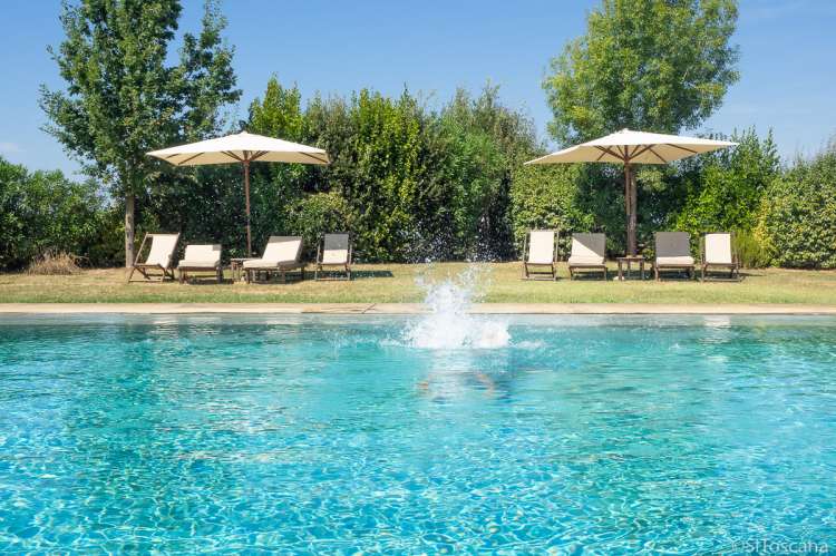 Bildet viser basseng, parasoller og solsenger på feriebosted ved Pisa i Italia.