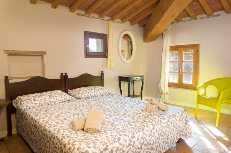 Bildet viser ett av soverommene i leiligheten Colombaia på vingården Borgo Etruschi, formidlet av SiToscana.