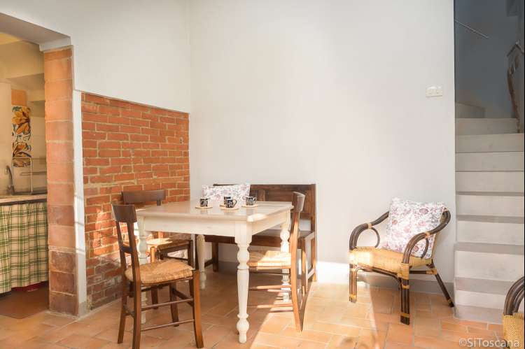 Bildet viser oppholdsrom med spisebord og dør inn til kjøkken i ferieleiligheten Segno på vingården Borgo Etruschi. Formidlet av SiToscana.